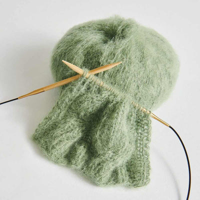 Green yarn with knitting needles on a white background | Yarn Worx