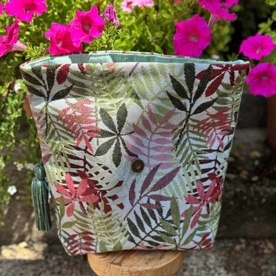 fabric project bag in pink and green sitting on a stool with pin flowers in the background