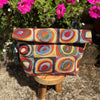 Colorful patterned bag on a wooden stool with flowers in the background
