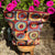 Colorful patterned bag with a tassel on a wooden stool against a background of pink flowers.