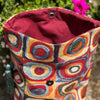 Colorful fabric bag with geometric pattern and tassels against a natural background