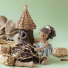 Knitted doll with a thatched-roof hut on a green background | Yarn Worx