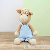 Crocheted alpaca toy wearing a blue outfit on a wooden surface with a light green background | Yarn Worx