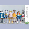 Knitted animal dolls wearing colorful clothing on a wooden bench against a light gray background | Yarn Worx