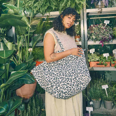 Woman holding a leopard print bag in a plant store | Yarn Worx