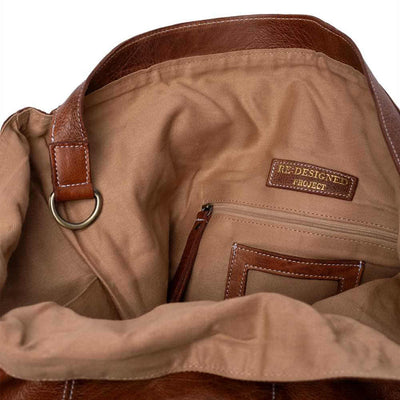 Close-up of a brown leather bag with a visible brand label on a white background | Yarn Worx