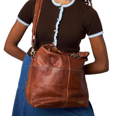 Brown leather handbag worn by a person on a white background | Yarn Worx