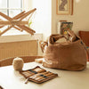 Brown leather bag and travel case on a table with a window and chair in the background | Yarn Worx
