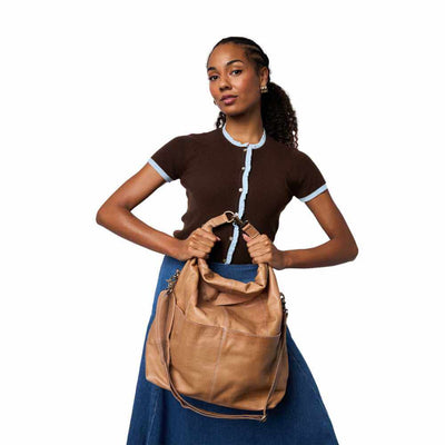 Woman holding a Taupe leather bag against a white background | Yarn Worx