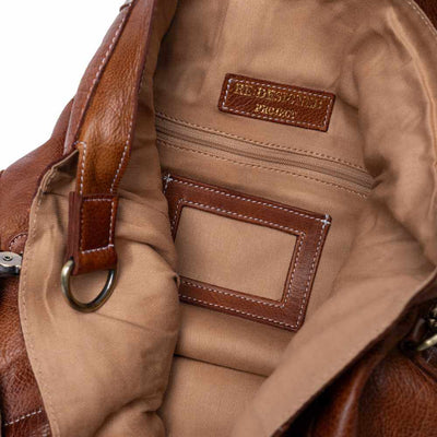 Close-up of a brown leather bag with visible stitching and a brand label | Yarn Worx