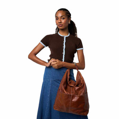 Woman holding a brown leather bag against a white background | Yarn Worx