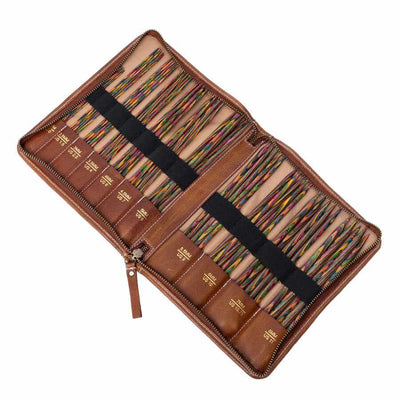 An open brown leather organizer case filled with many colourful double pointed knitting needles arranged in rows with black elastic bands and gold-coloured labels, on a plain white background | Yarn Worx