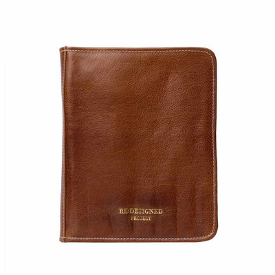 A brown leather knitting needle case with visible grain texture, white stitching, and gold embossed text reading 'RE-DESIGNED PROJECT' near the bottom, shown on a plain white background | Yarn Worx