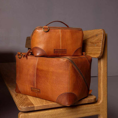 Two brown leather bags stacked on a wooden chair against a gray background | Yarn Worx
