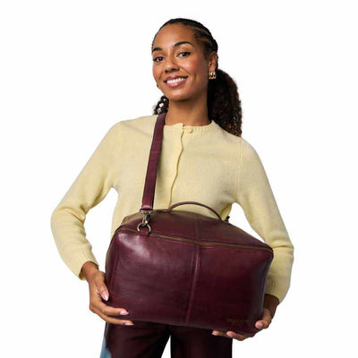 Woman holding a maroon dark cherry leather bag against a white background | Yarn Worx