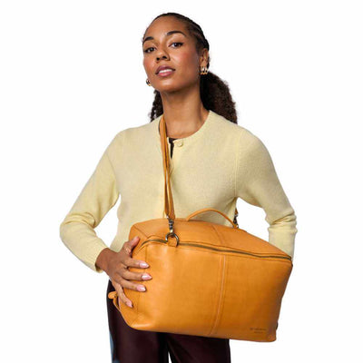 Woman holding a tan leather bag against a white background | Yarn Worx