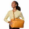 Woman holding a tan leather bag against a white background | Yarn Worx