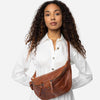 Woman holding a walnut brown leather bag against a white background