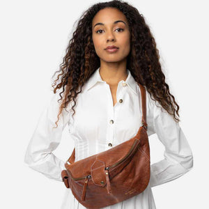 Woman holding a walnut brown leather bag against a white background