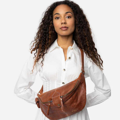 Woman holding a walnut brown leather bag against a white background