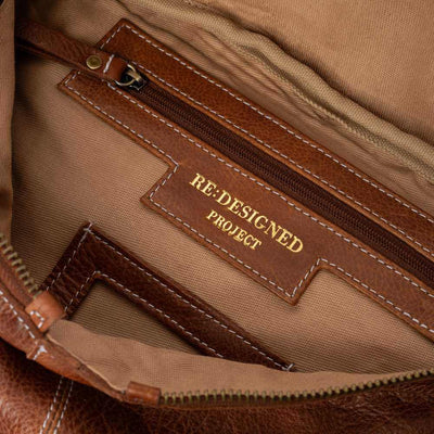Close-up of a brown leather bag with 'RE-DESIGNED PROJECT' label.