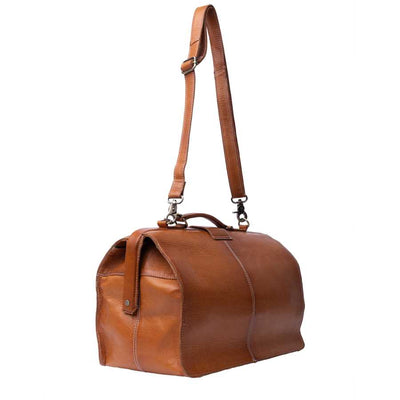 A brown leather doctors style bag with a top handle, adjustable shoulder strap, and burnished style hardware, shown on a plain white background | Yarn Worx