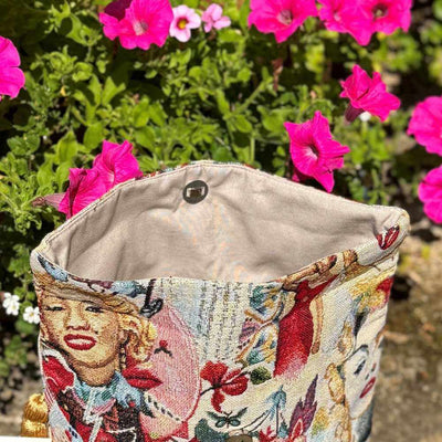 Embroidered bag with floral and portrait design in front of pink flowers