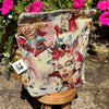 Decorative pillow with artistic designs of women on a stand with pink flowers in the background