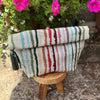 Striped fabric roll with tassels on a wooden stool outdoors