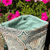 Patterned fabric bag with a green interior against a floral background