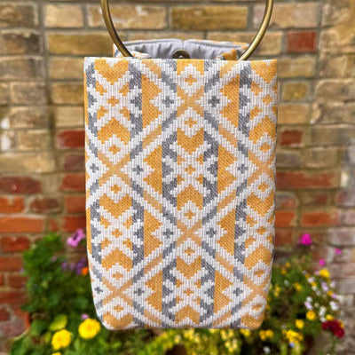 Patterned bag with a brick wall and flowers in the background