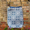 Blue and white patterned bag with gold handle against a brick wall.