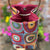 Colorful fabric pouch with a drawstring and handle against a blurred floral background