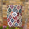 Fabric pouch with geometric pattern and brand tag on a blurred background