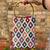 Handbag with geometric pattern held by a person against a brick wall.