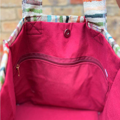 Red bag with a colorful handle against a brick wall background