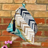 Fabric pouch with geometric pattern hanging against a brick wall