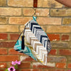 Fabric pouch with zigzag pattern and tassel against a brick wall