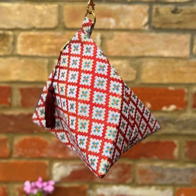 Decorative keychain with floral pattern against a brick wall