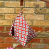 Small pouch with floral pattern and brown strap against a brick wall