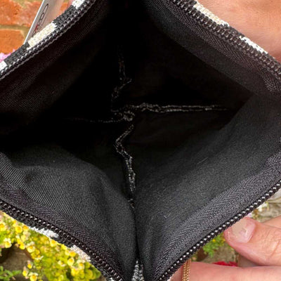 Close-up of a black sequin clutch bag held by a person.