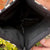 Close-up of a black sequin clutch bag held by a person.