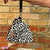 Leopard print drawstring bag with tassel against a brick wall
