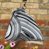 Triangular pouch with black and white pattern hanging against a brick wall.