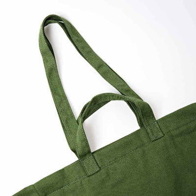 Close-up of an olive green canvas tote bag with double shoulder straps, showing the fabric texture and stitching against a plain white background | Yarn Worx