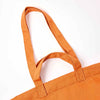 Close-up of an orange canvas tote bag showing the double shoulder straps and stitched attachment points against a plain white background | Yarn Worx