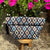 Patterned roll top bag on a wooden stool with pink flowers in the background