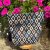Patterned pouch on a stool with pink flowers in the background