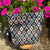 Patterned pouch on a stool with pink flowers in the background