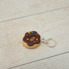 Donut-shaped keychain with chocolate glaze and sprinkles on a light wooden surface